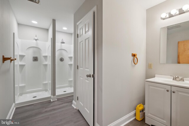 bathroom featuring walk in shower, hardwood / wood-style flooring, and vanity