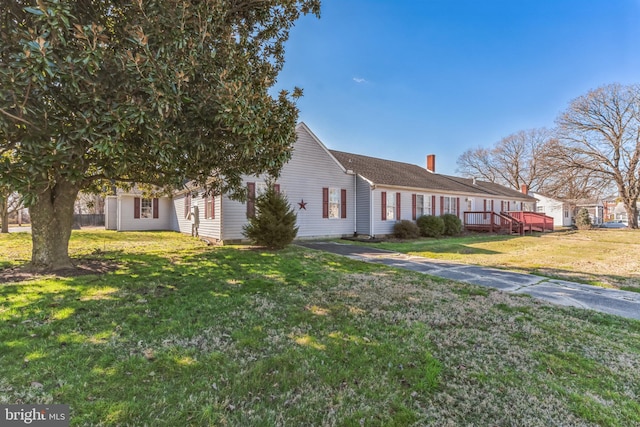 view of front facade featuring a wooden deck and a front lawn