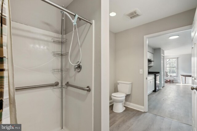 bathroom featuring hardwood / wood-style floors, an enclosed shower, vanity, and toilet