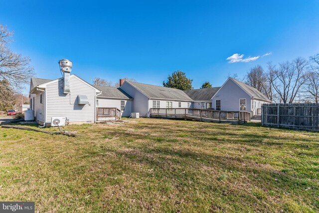 rear view of property featuring a wooden deck and a lawn