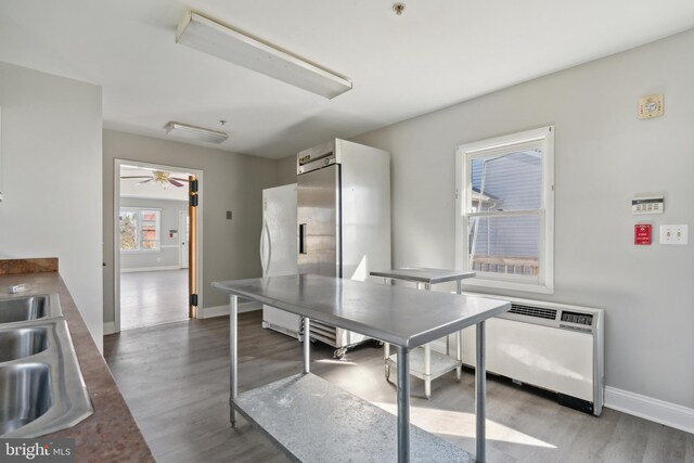 dining room with wood-type flooring, radiator heating unit, sink, and ceiling fan