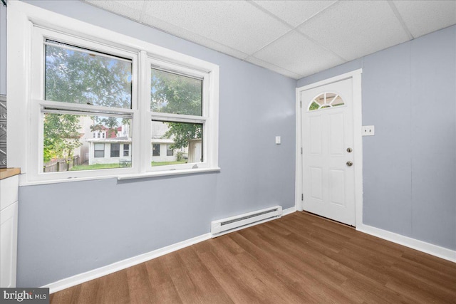 foyer entrance with baseboard heating, a paneled ceiling, and hardwood / wood-style floors