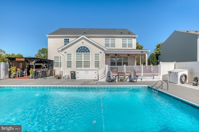 back of property with a fenced in pool, a patio area, ceiling fan, and pool water feature