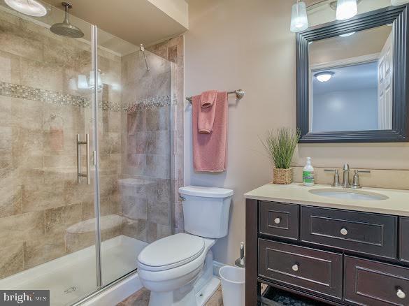 bathroom featuring vanity, a shower with shower door, and toilet