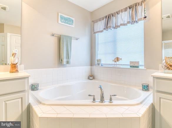 bathroom featuring vanity and tiled tub