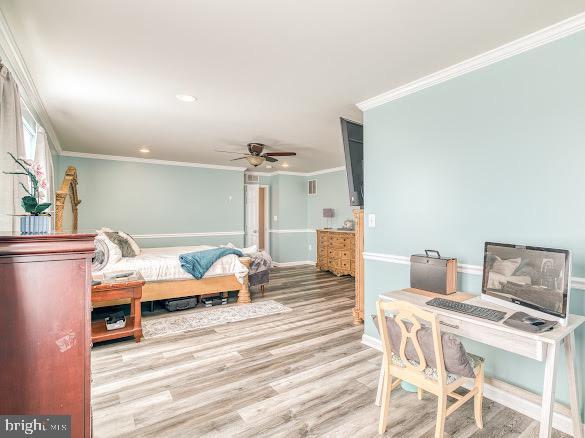 bedroom with hardwood / wood-style flooring, ceiling fan, and ornamental molding