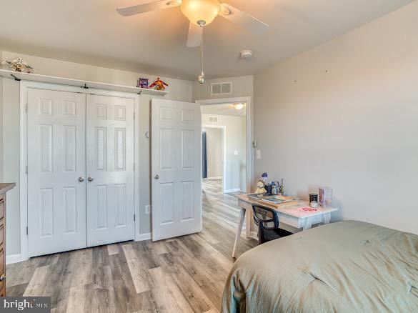 bedroom with ceiling fan, a closet, and light hardwood / wood-style flooring