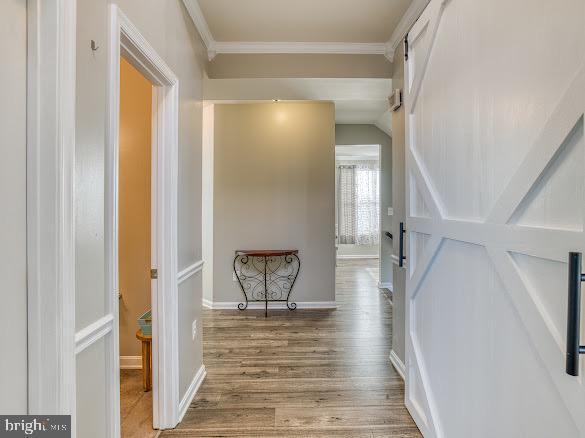 corridor with light hardwood / wood-style floors and crown molding