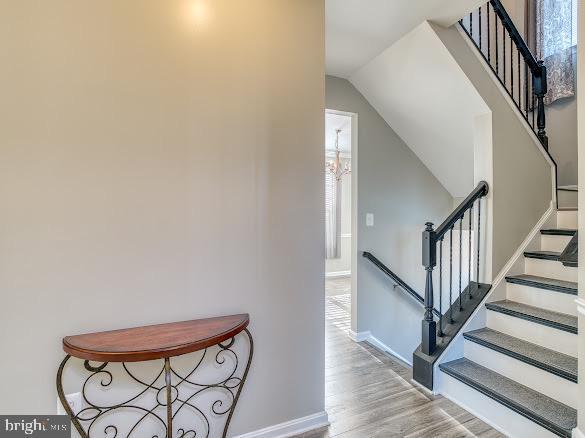 stairway with wood-type flooring and vaulted ceiling