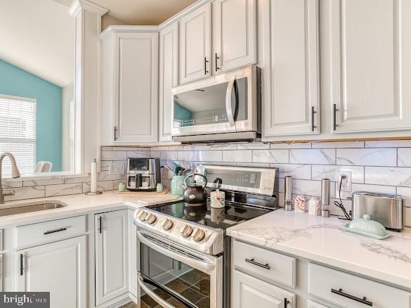 kitchen featuring sink, white cabinetry, stainless steel appliances, and tasteful backsplash