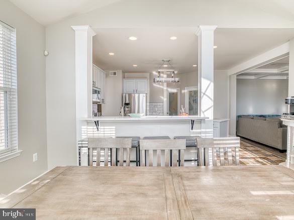 kitchen featuring a kitchen breakfast bar, stainless steel appliances, white cabinetry, and a healthy amount of sunlight