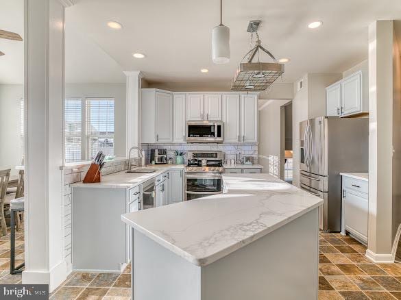 kitchen featuring white cabinets, decorative light fixtures, stainless steel appliances, and sink