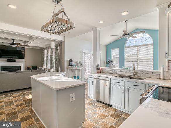 kitchen featuring sink, stainless steel dishwasher, a wealth of natural light, a kitchen island, and white cabinetry