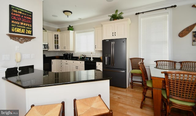 kitchen featuring sink, light hardwood / wood-style flooring, ornamental molding, kitchen peninsula, and black appliances