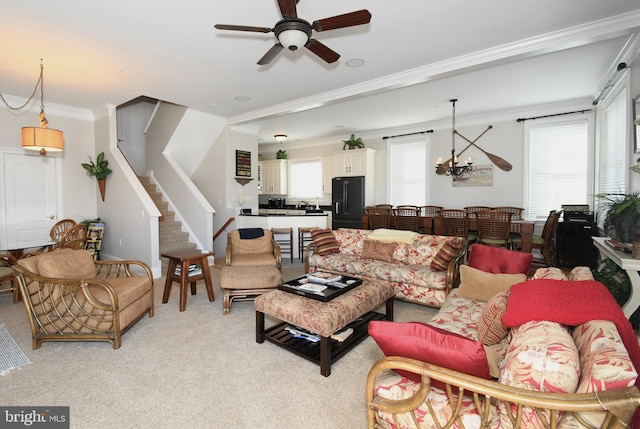 living room with light colored carpet, ornamental molding, ceiling fan with notable chandelier, and plenty of natural light