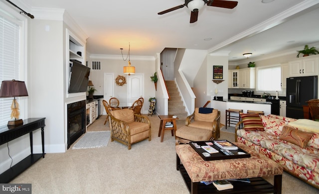 carpeted living room featuring sink, ornamental molding, and ceiling fan