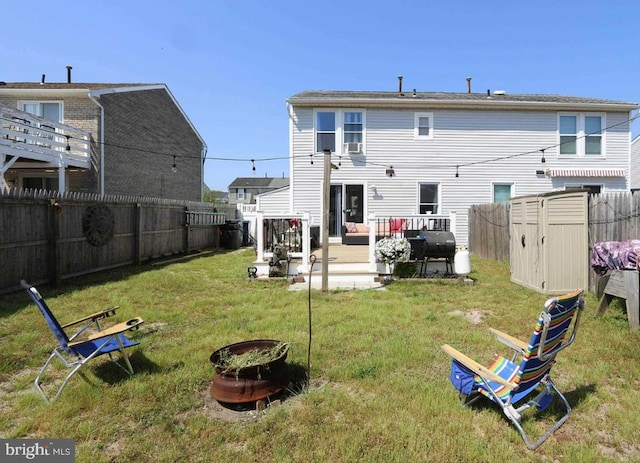 back of property featuring an outdoor fire pit, a shed, a yard, and a deck