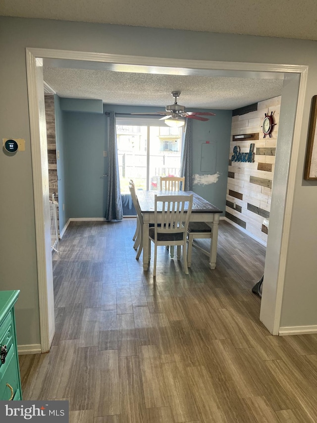 dining space with hardwood / wood-style flooring, ceiling fan, and a textured ceiling