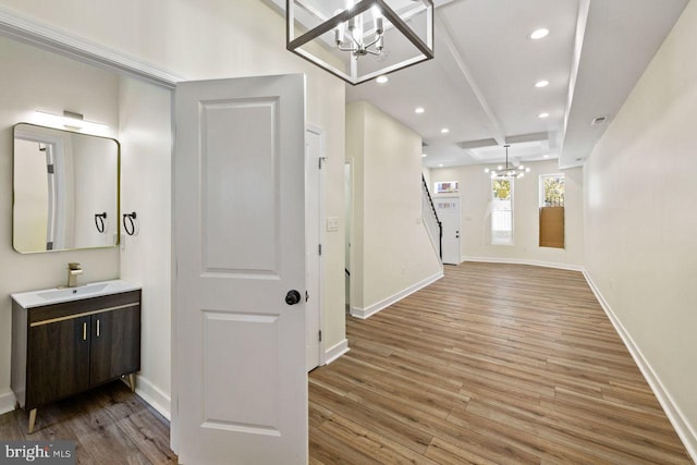 hall with beamed ceiling, hardwood / wood-style floors, a chandelier, and sink