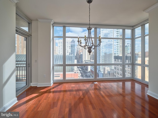 unfurnished dining area with an inviting chandelier, expansive windows, hardwood / wood-style flooring, and crown molding