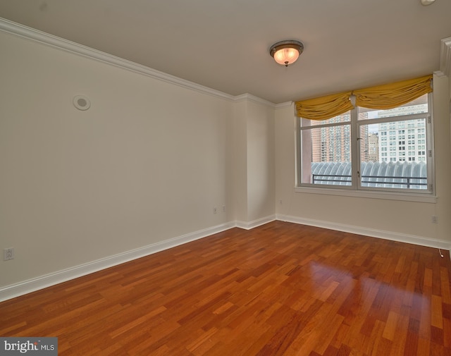 empty room featuring ornamental molding and wood-type flooring