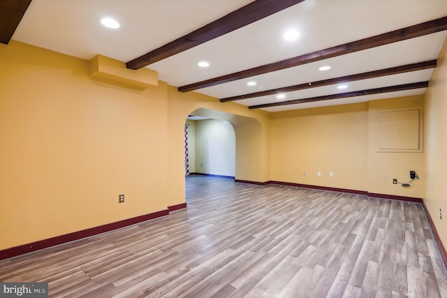 unfurnished room with beam ceiling and light hardwood / wood-style flooring