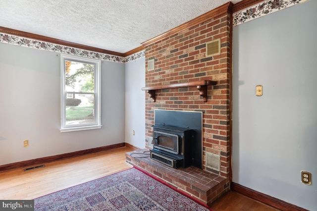 unfurnished living room with hardwood / wood-style flooring, a textured ceiling, a wood stove, and crown molding