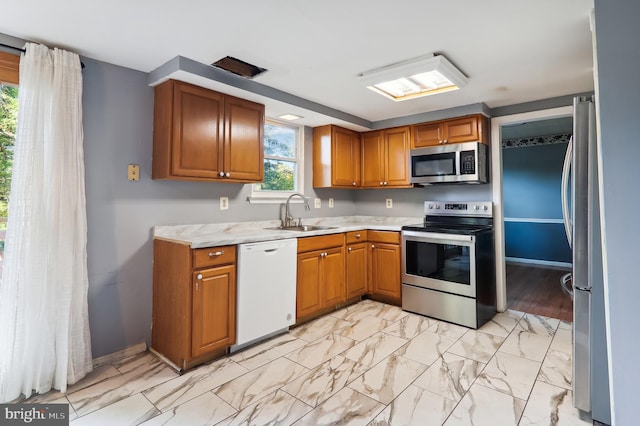 kitchen featuring stainless steel appliances, light stone countertops, sink, and light hardwood / wood-style flooring