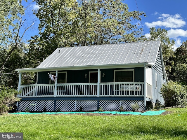 rear view of property featuring covered porch and a yard