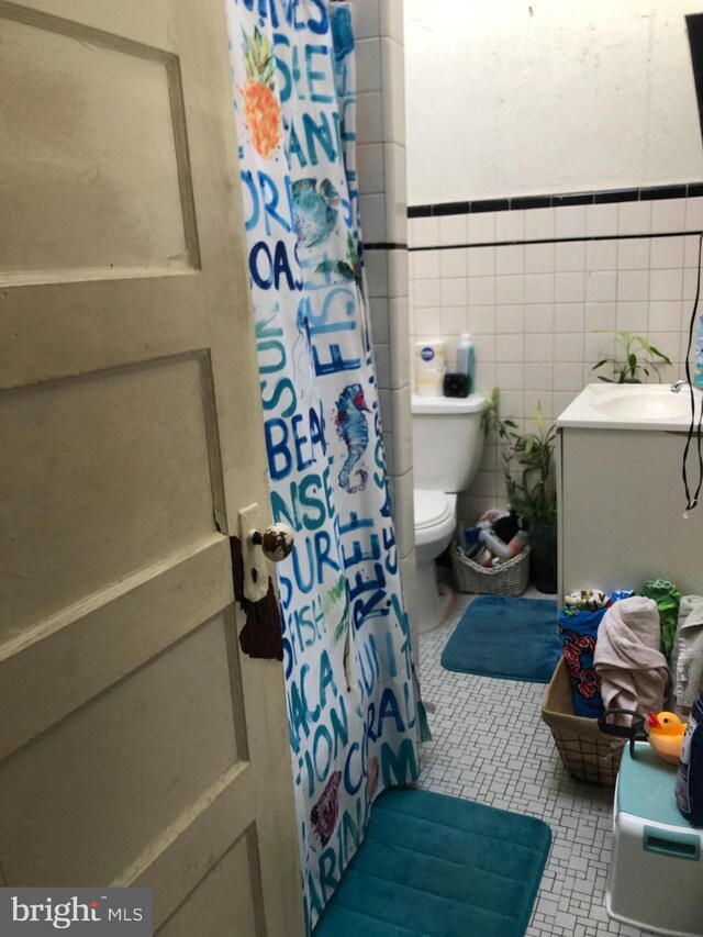 bathroom featuring walk in shower, vanity, tile walls, and toilet