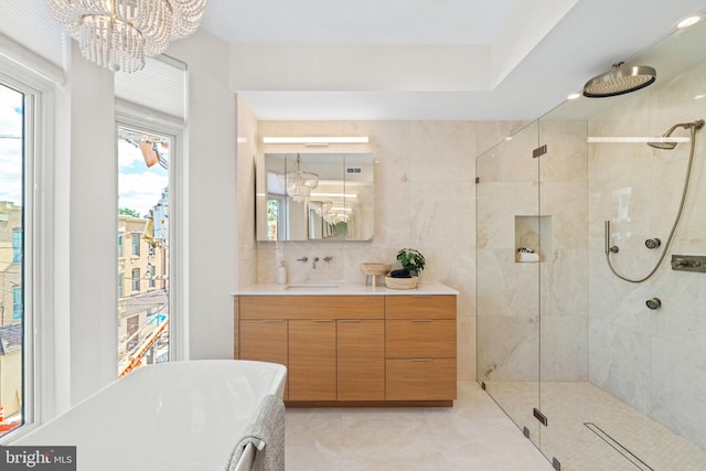 full bath with a soaking tub, a shower stall, vanity, and an inviting chandelier