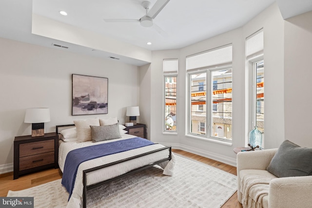 bedroom with light wood-style floors, visible vents, baseboards, and multiple windows