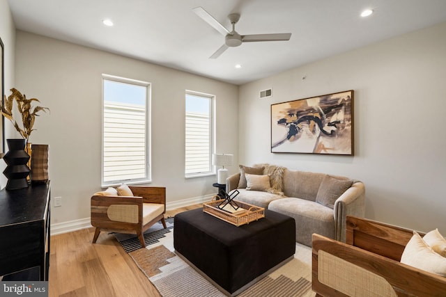 living area with a ceiling fan, visible vents, light wood-style flooring, and baseboards