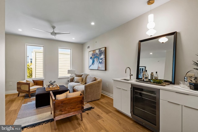 interior space featuring light hardwood / wood-style floors, wet bar, beverage cooler, and ceiling fan