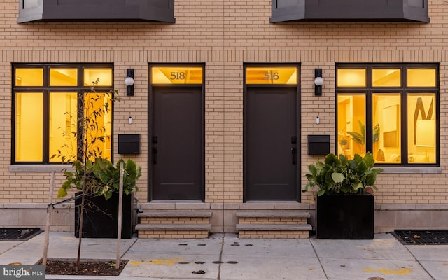 entrance to property featuring elevator and brick siding