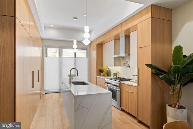 kitchen with stainless steel range, light hardwood / wood-style flooring, wall chimney exhaust hood, and sink