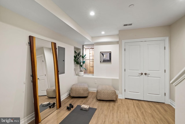 workout area with electric panel and light wood-type flooring