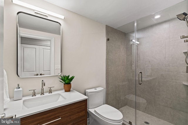 bathroom featuring vanity, toilet, and a shower with shower door