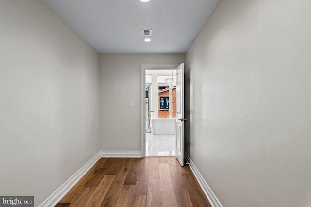 corridor with hardwood / wood-style flooring and a chandelier