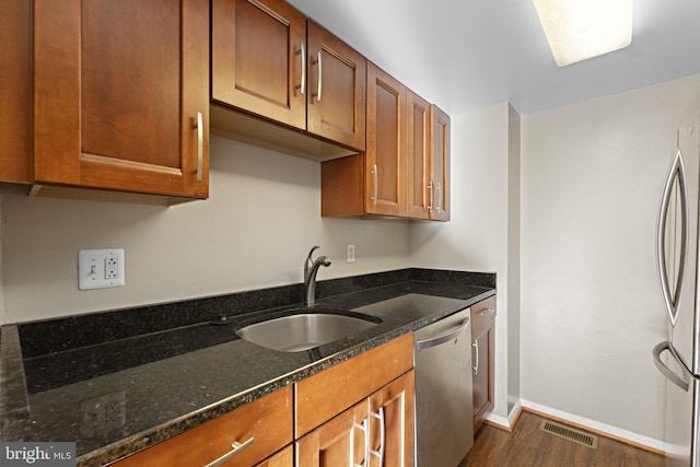 kitchen with dark stone counters, dark wood-type flooring, sink, and stainless steel appliances