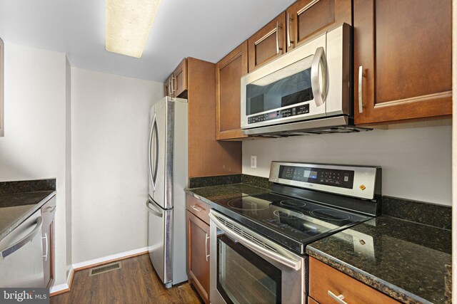 kitchen with dark stone counters, dark wood-type flooring, and stainless steel appliances