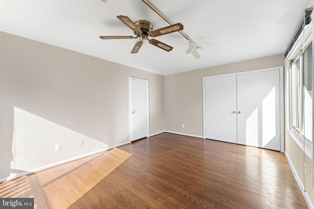 unfurnished bedroom featuring track lighting, hardwood / wood-style flooring, multiple windows, and ceiling fan