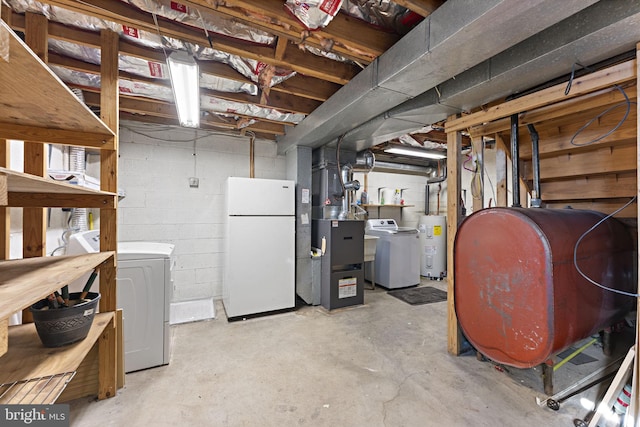 basement with washer and clothes dryer, water heater, and white fridge