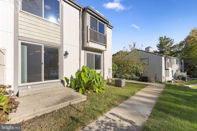 view of side of home with central AC unit and a yard