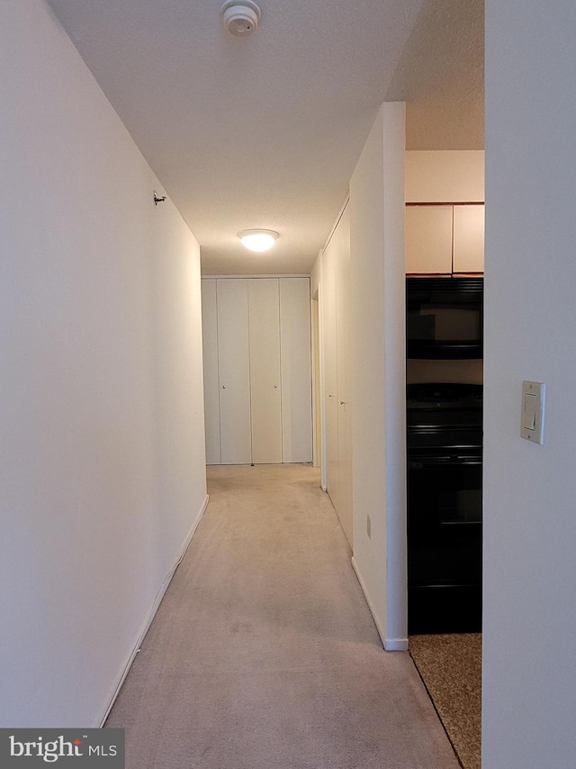 corridor with a textured ceiling and light colored carpet