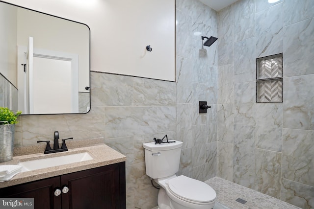 bathroom featuring toilet, tiled shower, tile walls, and vanity