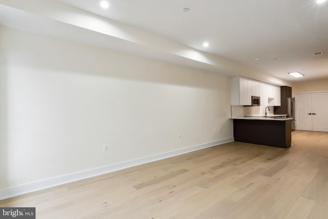 kitchen with kitchen peninsula, stainless steel appliances, light hardwood / wood-style floors, sink, and white cabinets