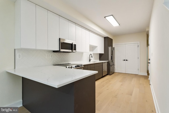 kitchen featuring kitchen peninsula, appliances with stainless steel finishes, and white cabinets