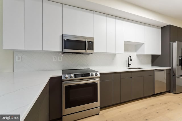 kitchen featuring white cabinetry, sink, light stone counters, and stainless steel appliances