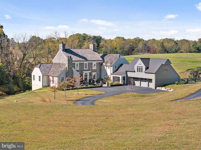 view of front facade with a front lawn, metal roof, a garage, driveway, and a standing seam roof